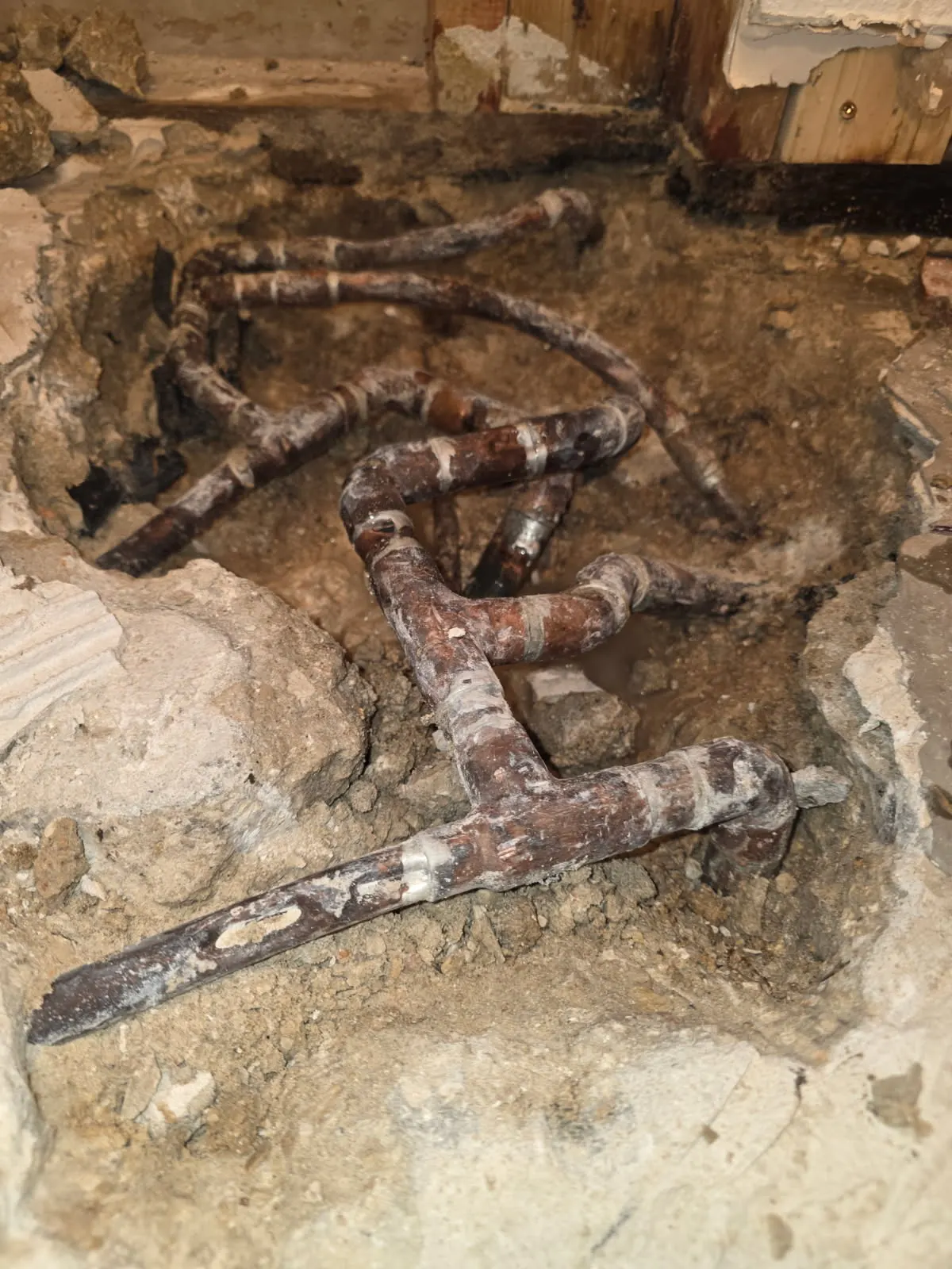 Before: corroded copper water supply lines exposed in a broken concrete slab