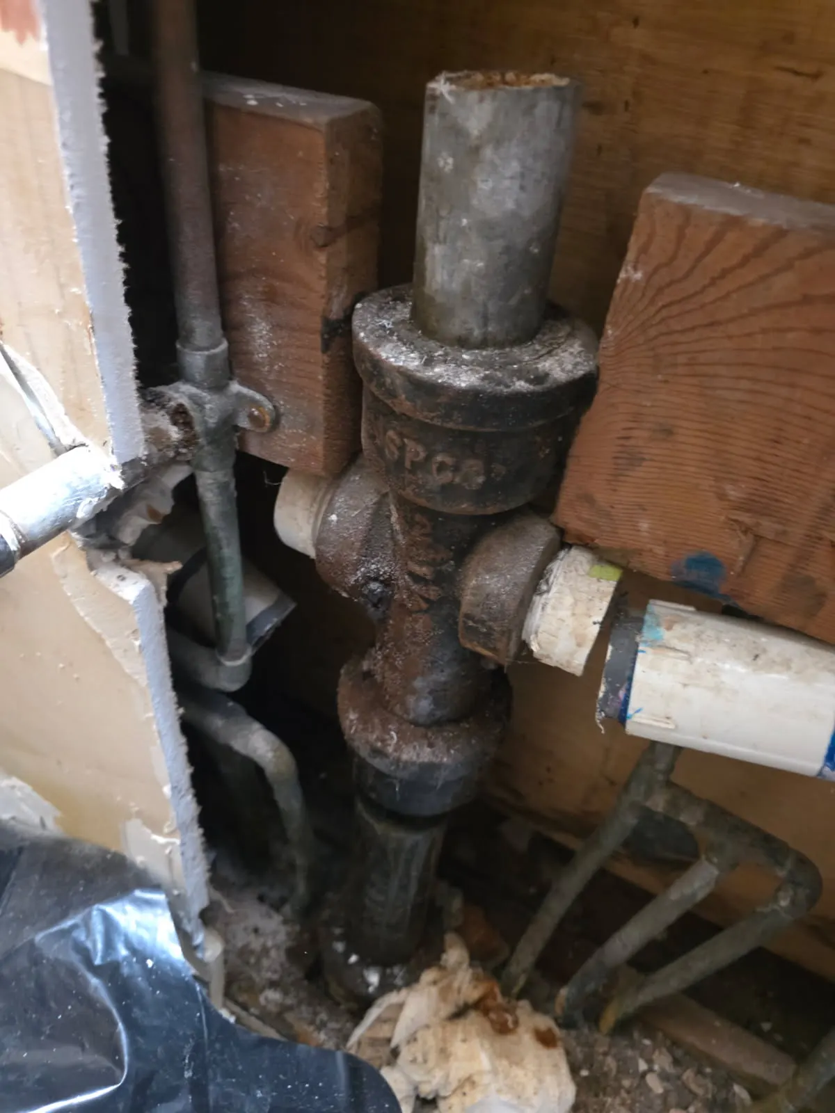 Before: rusted and corroded cast iron drain pipe fitting exposed in an opened wall