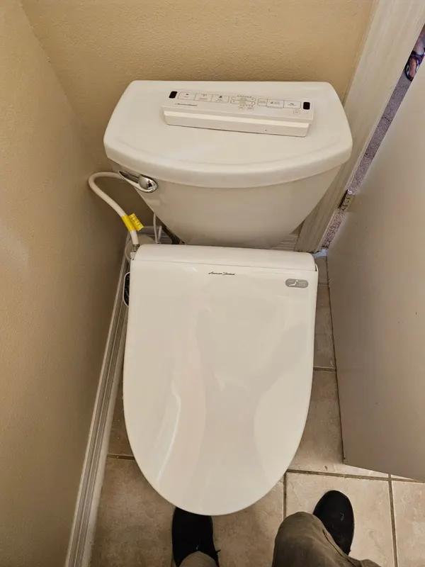 American Standard electronic bidet seat installed on a residential toilet in San Antonio — supply T-fitting and side control panel wired in by Out This World Services