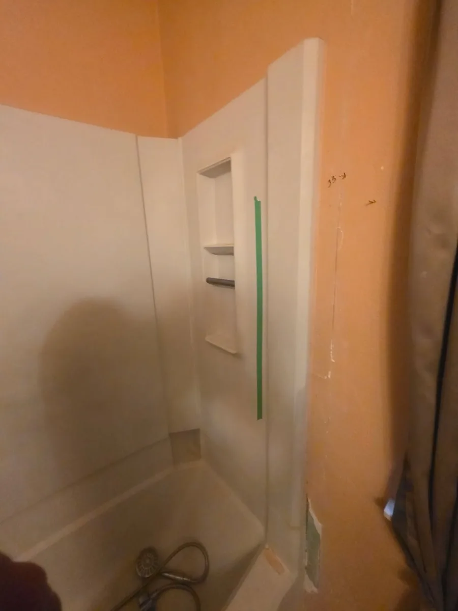 Old white shower insert with orange bathroom walls before remodel