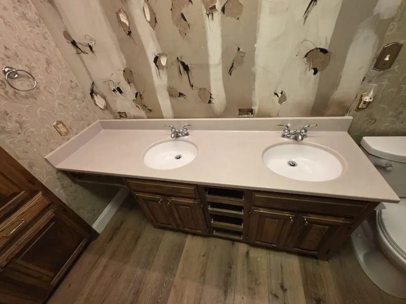 Existing double-sink cultured-marble vanity on dark oak base — before shot of a San Antonio bathroom vanity replacement by Out This World Services