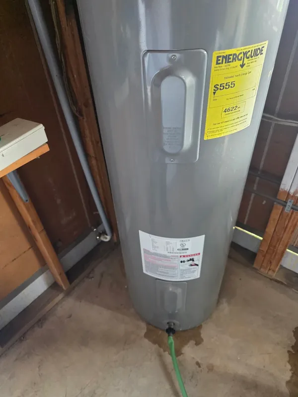 New 50-gallon electric water heater installed and connected with insulated lines and EnergyGuide label still on the tank