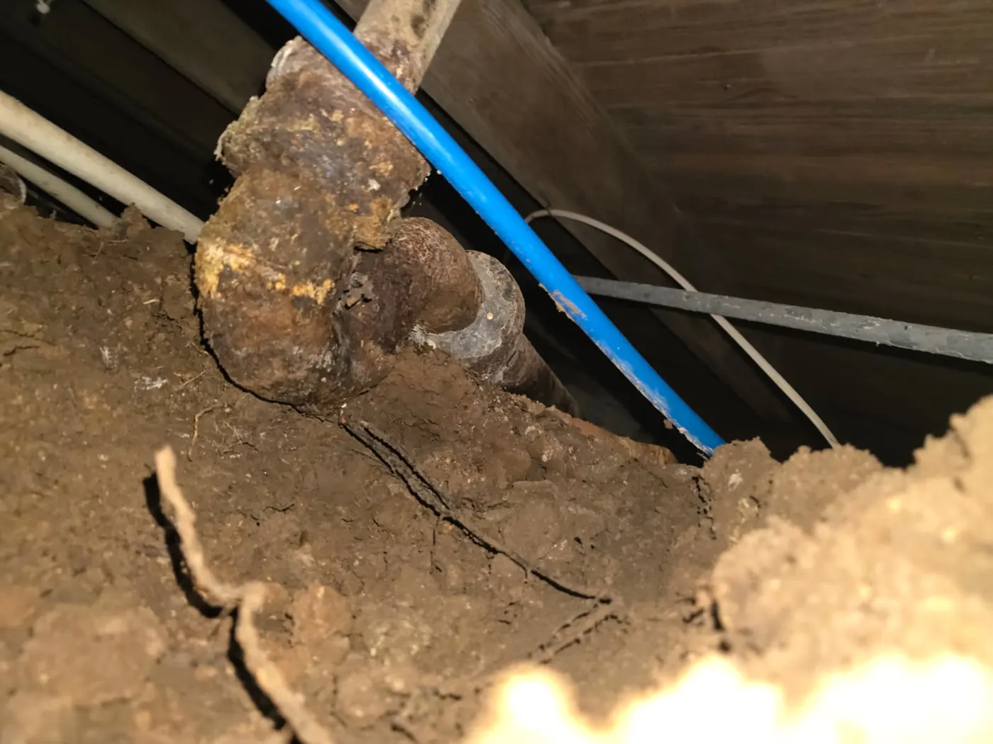 Heavily rusted cast iron drain fitting with corroded joint in a San Antonio crawlspace — before Out This World Services replaced the run with new PVC drain line