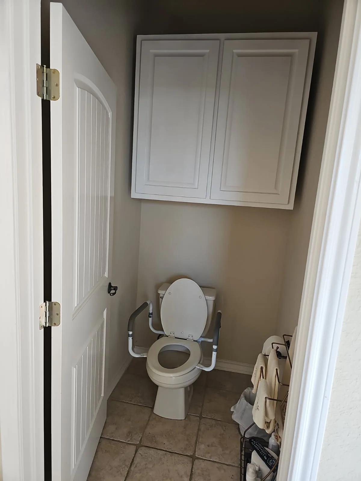 Standard-height toilet fitted with an ADA safety frame and padded handrails for aging-in-place — grab bar and toilet safety accessory install by Out This World Services in San Antonio