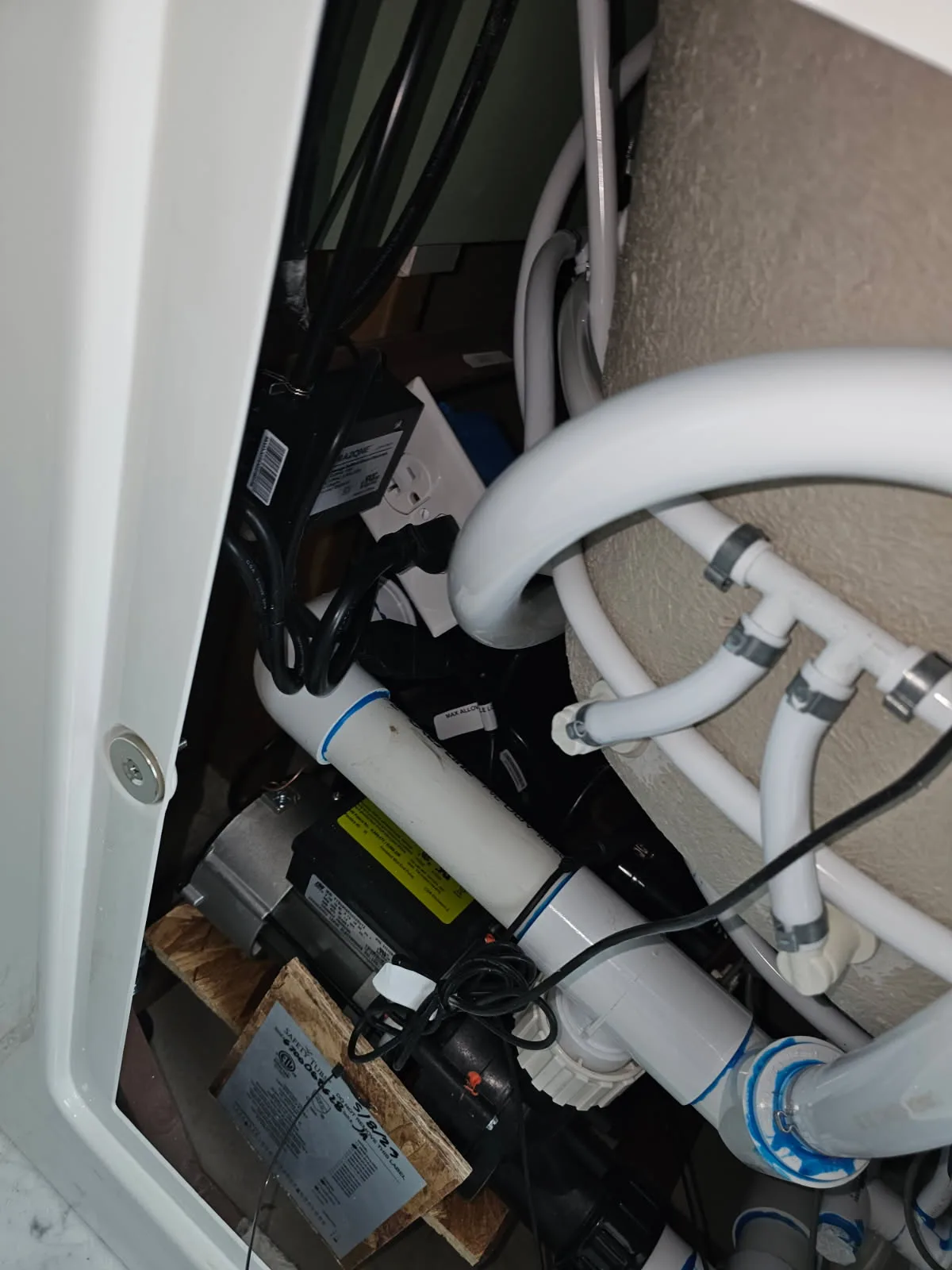 Close-up of a walk-in tub's internal components — pump, ozone unit and flex plumbing lines exposed during a repair and maintenance service call by Out This World Services